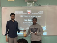 a man holding a certificate in front of a classroom