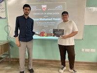 two men standing next to each other holding a certificate