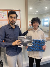 two men standing next to each other holding a certificate